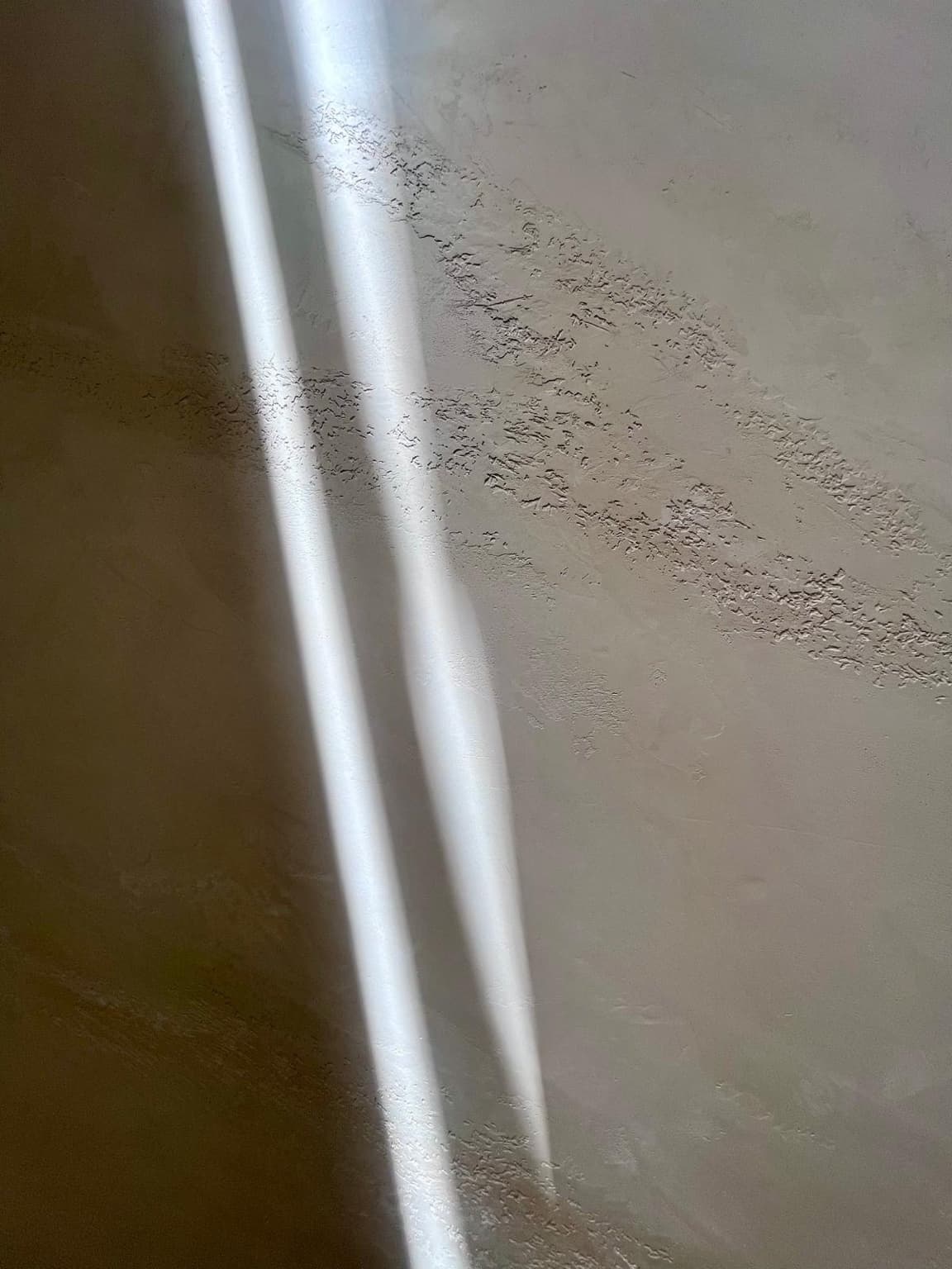 Natural light revealing the movement of a hand-applied plaster surface